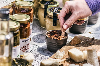 Hand dipping bread into rustic tomato pesto spread