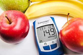 Blood Glucose Meter Displaying 14.9 mmol/L Beside Fresh Apples and Banana