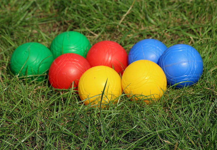 Colorful plastic balls arranged on green grass