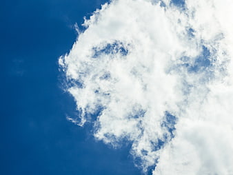 White Fluffy Clouds Against Deep Blue Sky Background
