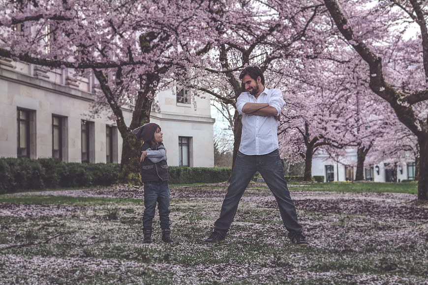 Father and son standing under blooming cherry blossom trees