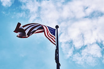 American Flag Waving Against Blue Sky with Clouds
