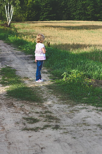 Little girl standing on dirt path in summer field