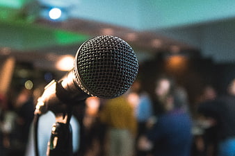 Close-up of microphone on stage with blurred crowd background