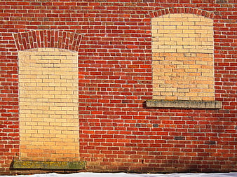 Red brick wall with bricked-up windows and stone sills