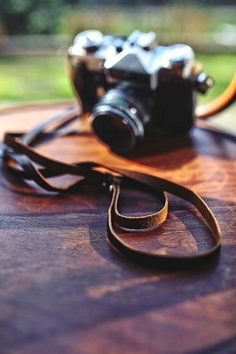 Vintage Film Camera with Leather Strap on Wooden Table