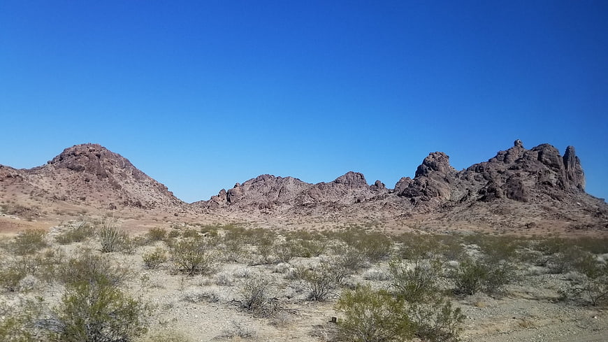 Wide desert landscape with rocky mountains and blue sky