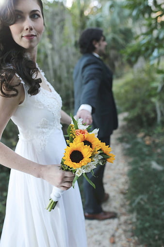 Bride with Sunflower Bouquet and Groom in Background