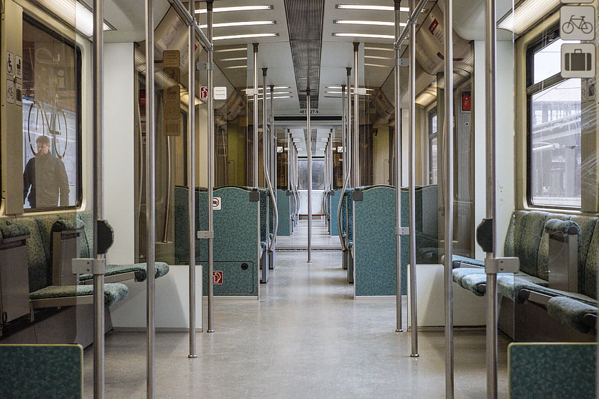 Empty subway car interior with green seats and metal poles