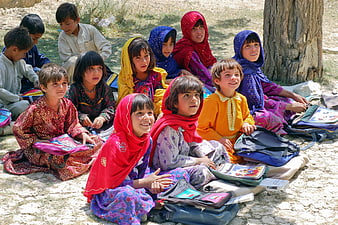 Group of Afghan schoolchildren sitting outdoors with books