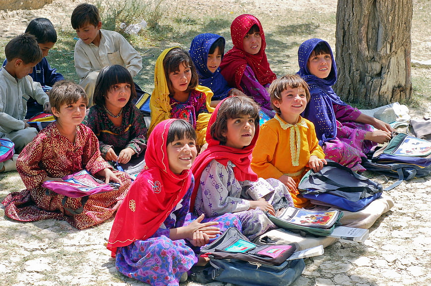 Group of Afghan schoolchildren sitting outdoors with books