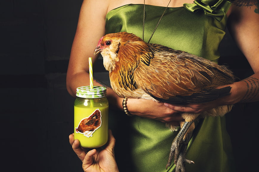 Woman holding chicken with green smoothie in jar