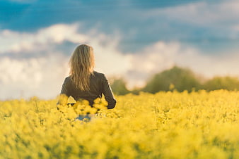 Woman Sitting in Yellow Flower Field at Sunset