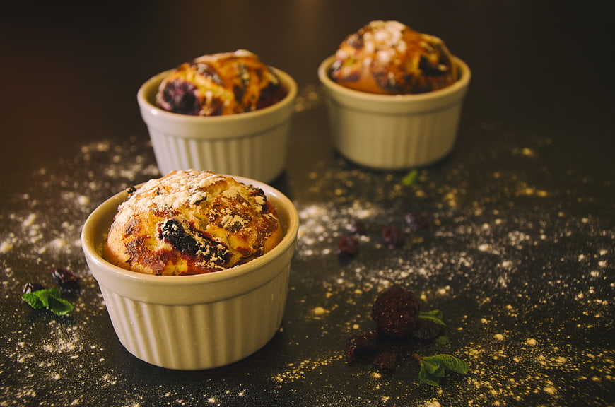 Rustic baked berry soufflés in ramekins with powdered sugar