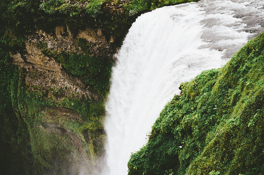Powerful waterfall cascading down mossy green cliffs