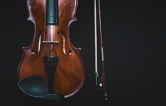Close-up of a wooden violin and bow on a black background