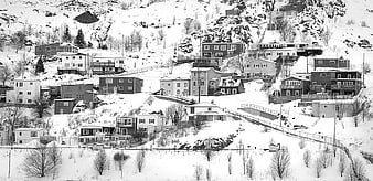 Snow-covered houses on a steep mountain slope in black and white