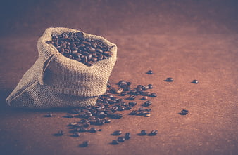 Rustic burlap sack of roasted coffee beans on wooden table