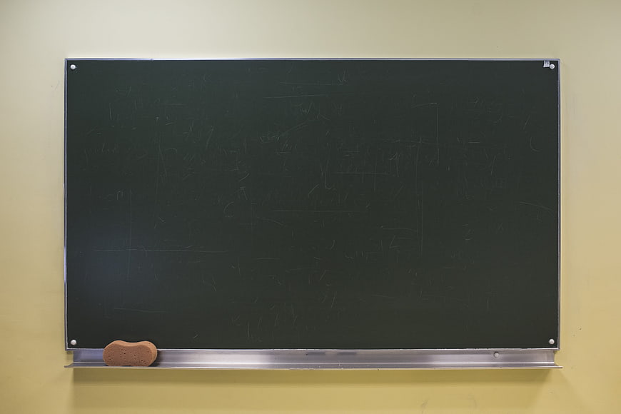 Empty Blackboard With Chalk Eraser On Yellow Wall