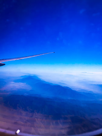 Aerial view of mountains from airplane window with wing