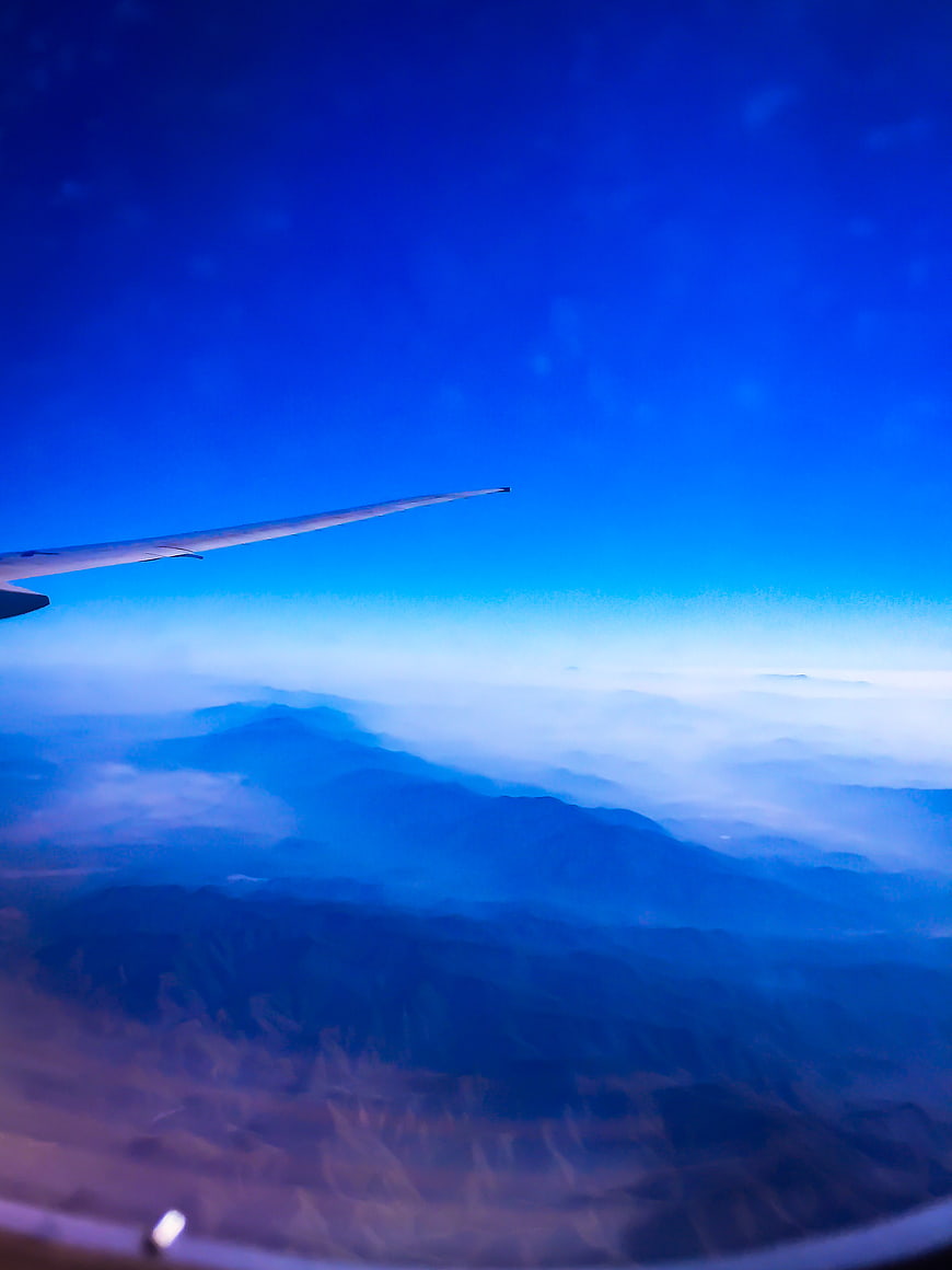 Aerial view of mountains from airplane window with wing