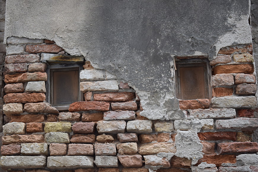 Weathered Brick Wall with Peeling Plaster and Old Windows