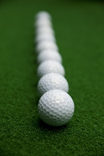 Line of golf balls on green grass with shallow depth of field