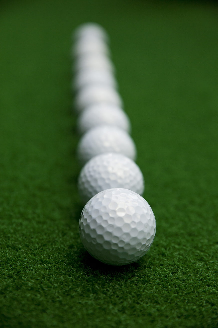 Line of golf balls on green grass with shallow depth of field