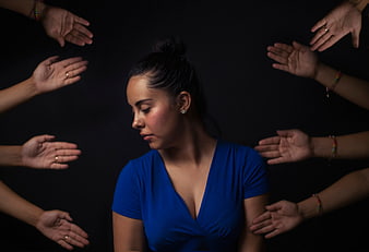 Woman surrounded by reaching hands on black background