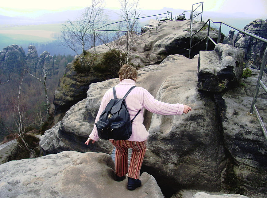 Woman hiking on rocky sandstone mountain trail with backpack
