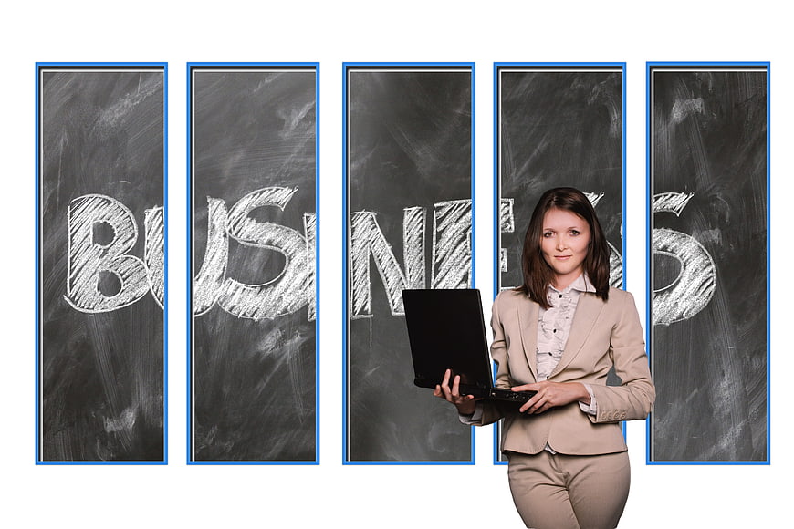 Businesswoman holding laptop in front of chalkboard with business text