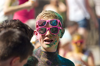 Boy with Pink Sunglasses and Colorful Paint at Festival