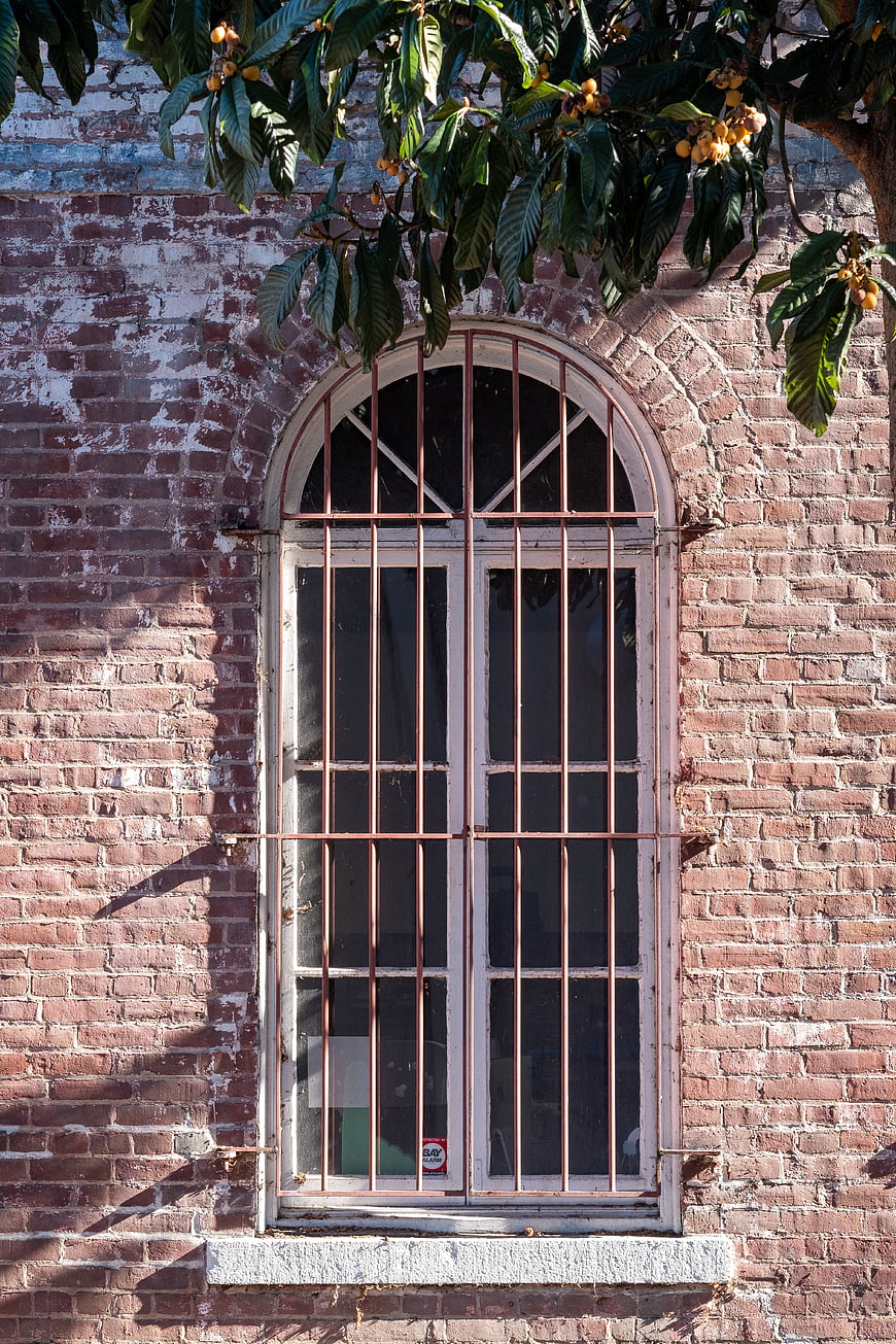 Arched window with bars on weathered brick wall