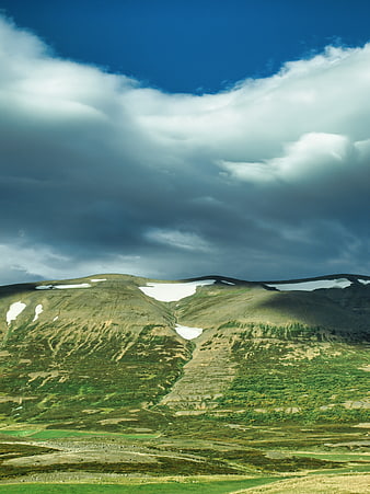 Dramatic Mountain Landscape with Snow Patches and Cloudy Sky