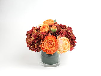 Autumn floral arrangement with orange roses and red hydrangeas in a glass vase
