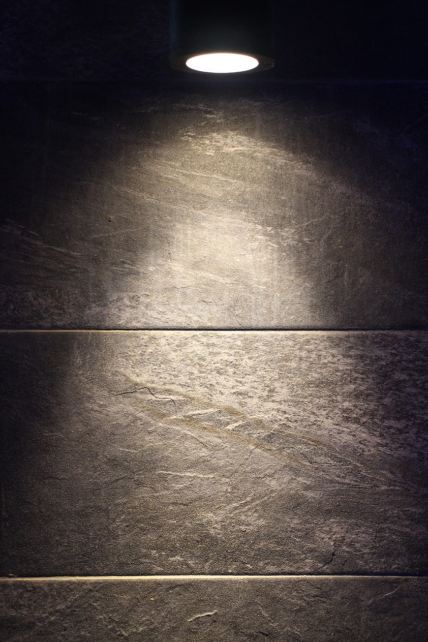 Dark Textured Stone Wall Illuminated By Single Ceiling Spotlight