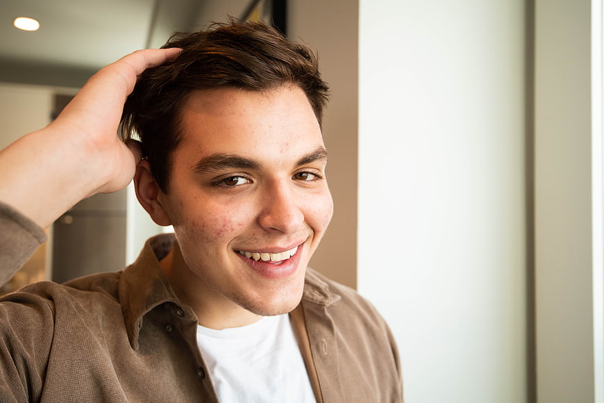 Smiling young man running hand through hair indoors