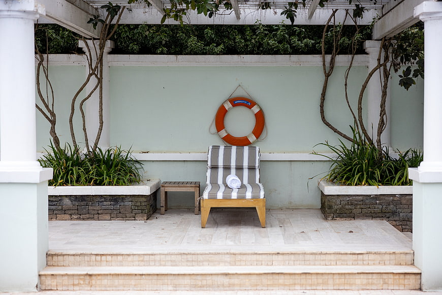 Symmetrical Poolside Lounge with Striped Chair and Lifebuoy