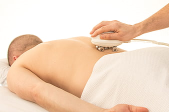 Therapist using massage device on man's back