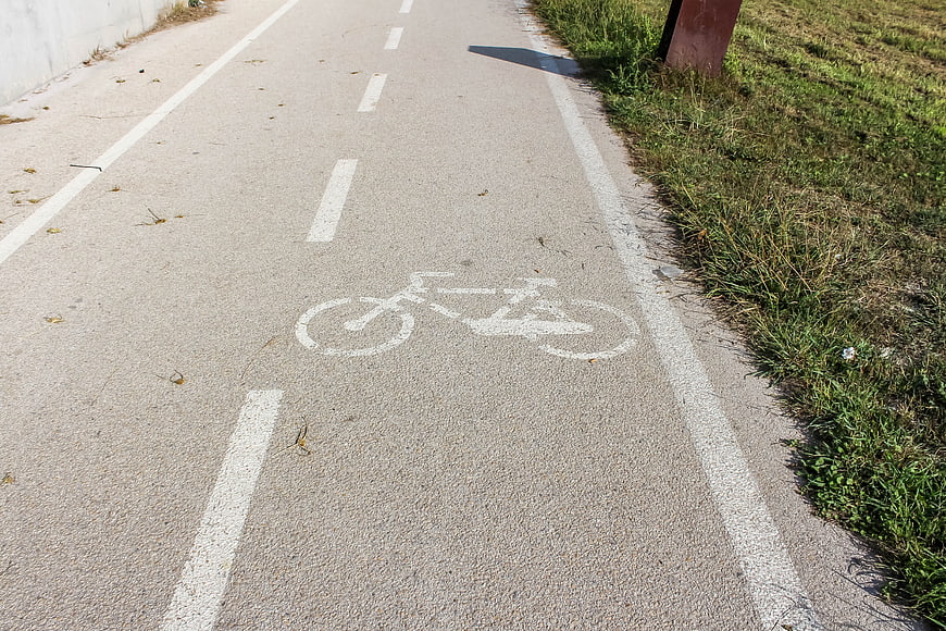 Paved bicycle path with white bike symbol and grass
