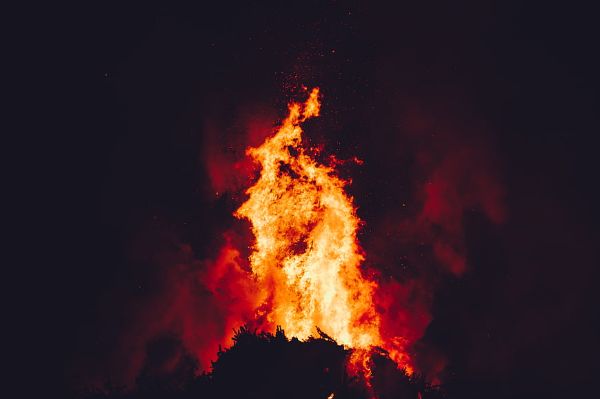 Intense bonfire flames burning against a dark night sky
