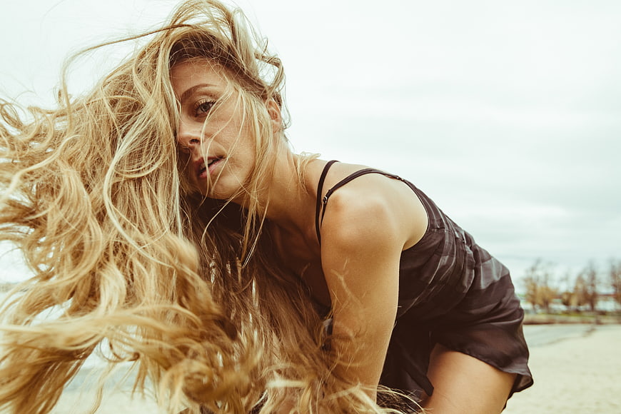 Blonde Woman with Windblown Hair on Sandy Beach