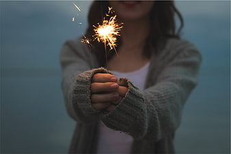 Woman holding sparkler in cozy cardigan