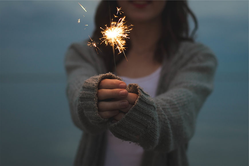 Woman holding sparkler in cozy cardigan