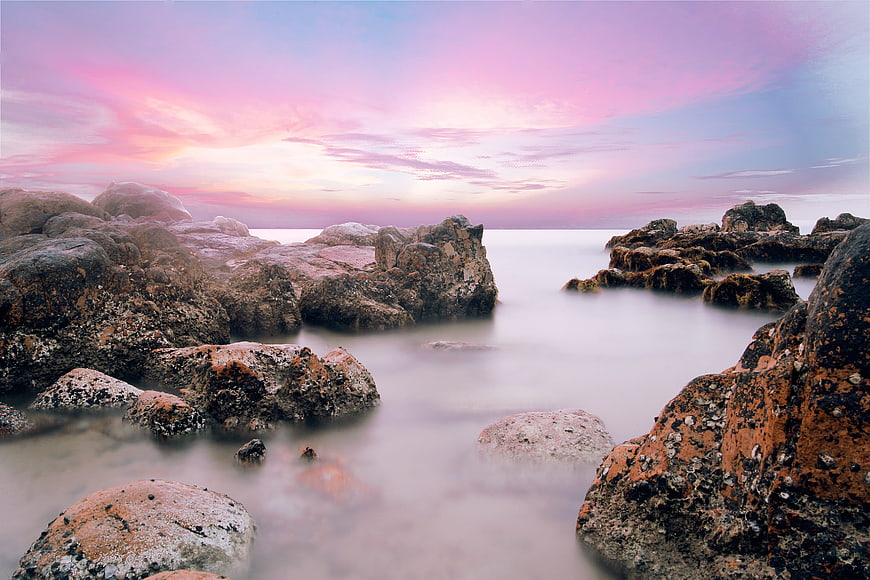 Long Exposure Pink Sunset Over Rocky Coastal Shoreline