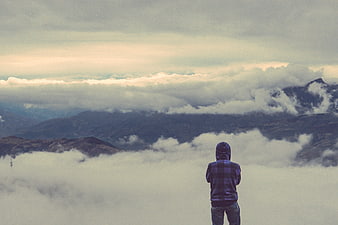 Man in Hoodie Looking at Mountain Clouds
