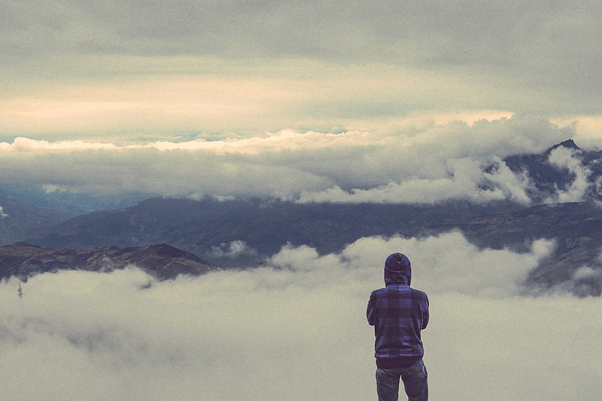 Man in Hoodie Looking at Mountain Clouds