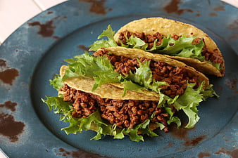 Three beef tacos with lettuce on a rustic blue plate