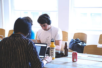 Young men collaborating on laptops in a bright office workspace