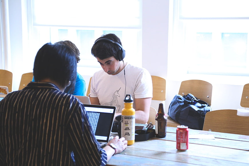 Young men collaborating on laptops in a bright office workspace